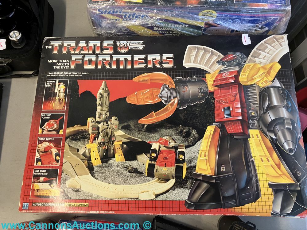 Vintage 1983 Hasbro Transformers Omega Supreme boxed set showing robot and tank forms with accessories and original packaging.