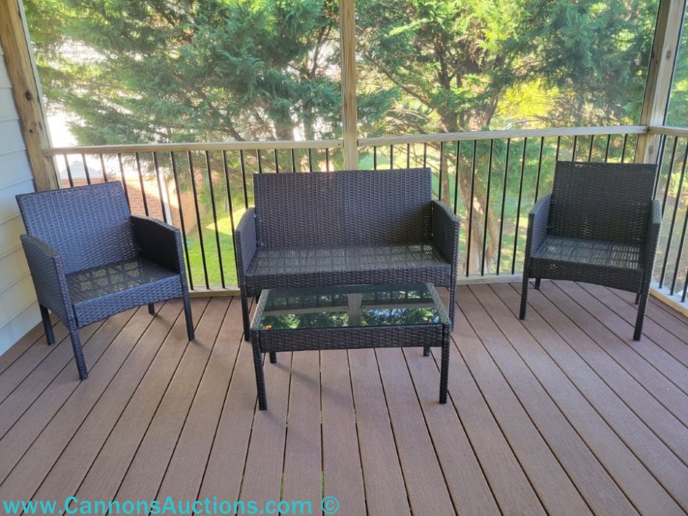 Four piece set of all-weather wicker patio furniture including two armchairs, a loveseat, and a glass top coffee table.