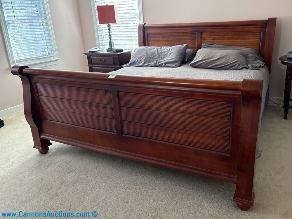 King size solid wood sleigh bed with paneled headboard and footboard, shown assembled in bedroom; measures 81” x 91”.