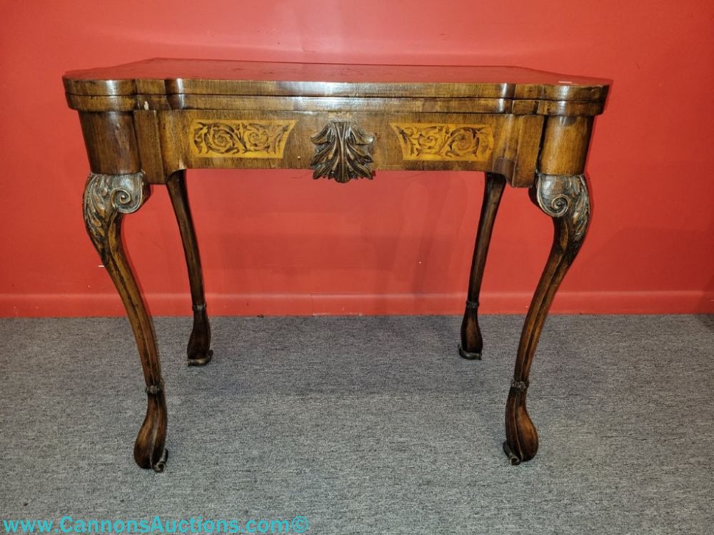 Antique ornate marquetry inlaid flip top game table with carved acanthus leaf detail, cabriole legs, and Flemish feet, shown closed