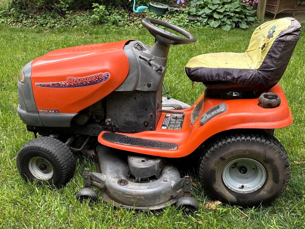 Husqvarna YTH 2148 riding lawn tractor in working condition with orange body, mower deck, steering wheel, and yellow seat