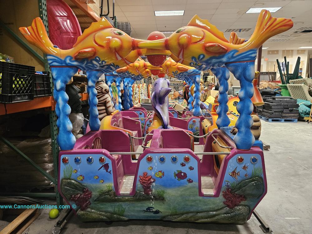 Four colorful amusement ride cars with aquatic animal designs, fish graphics, dolphin center figure, and sea-themed canopy in Children’s Museum Richmond auction.