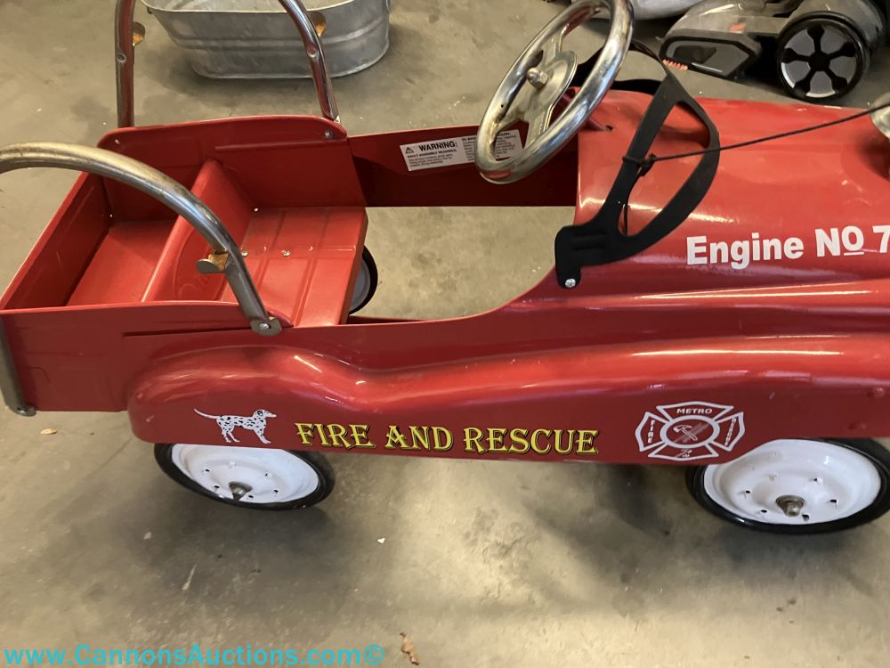 Red metal fire and rescue pedal car with chrome accents, bell, white wheels, Engine No. 7 lettering, and fire department decals.