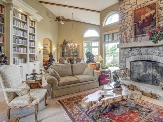 Elegant Keswick estate living room with bronze statues, original art, oriental rug, bookshelves, fireplace, sofa, chairs, and carved wood coffee table