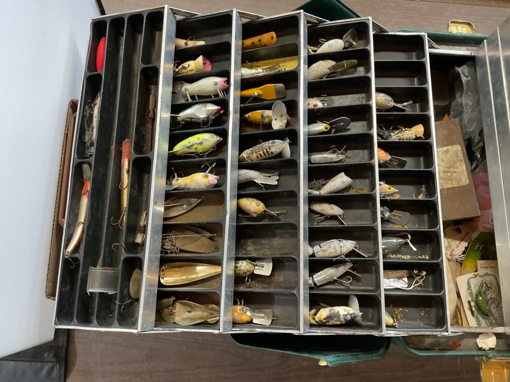 Large vintage Umco fiberglass tackle box with assorted fishing lures, plugs, spoons, and tackle contents