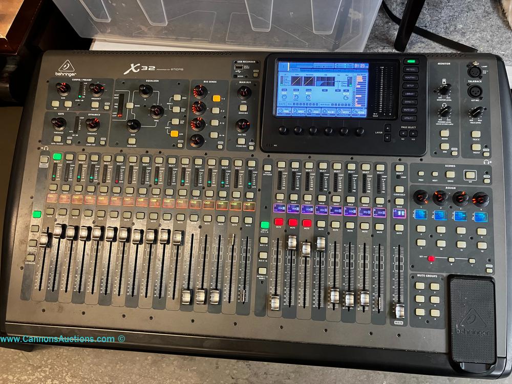 Behringer X32 digital mixing console with multiple faders, control knobs, display screen, and channel controls