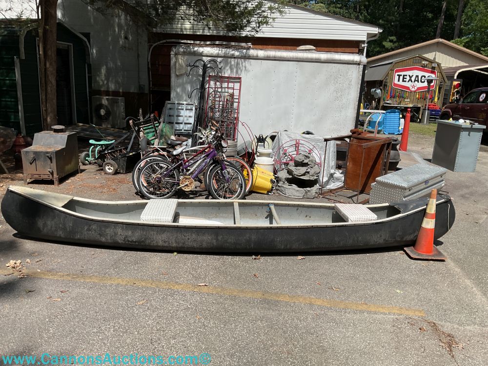 Vintage aluminum canoe with bench seats and pointed bow, displayed outdoors at Yellow Gate Place